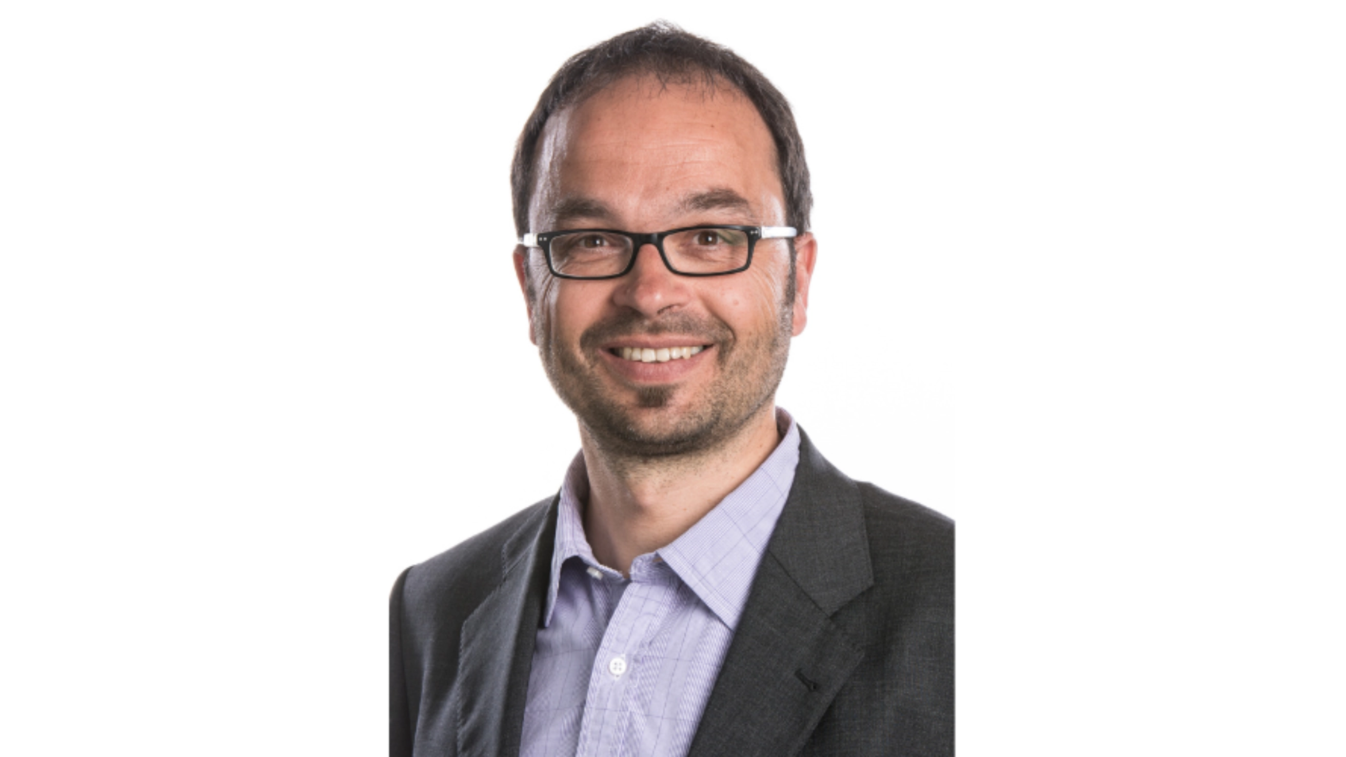 Christoph Heitz lächelt in die Kamera. Er trägt eine Brille, ein hellviolettes Hemd und ein Jackett.