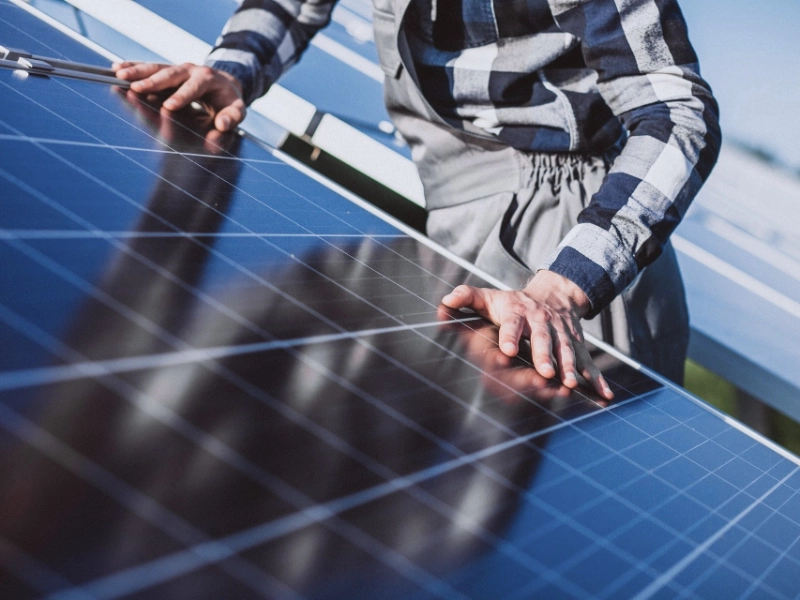 Solarmodul, auf dem zwei Hände zu sehen sind. 