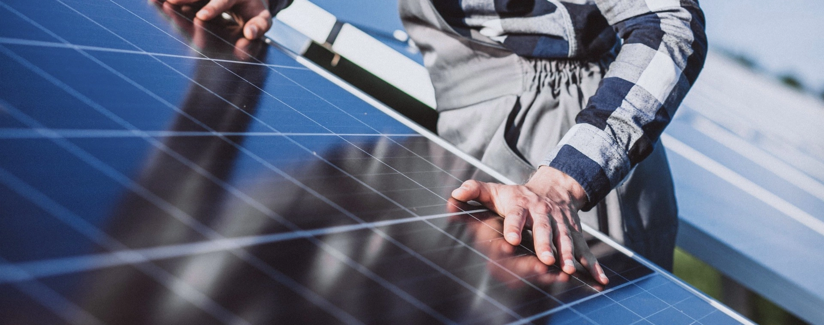 Solarmodul, auf dem zwei Hände zu sehen sind. 